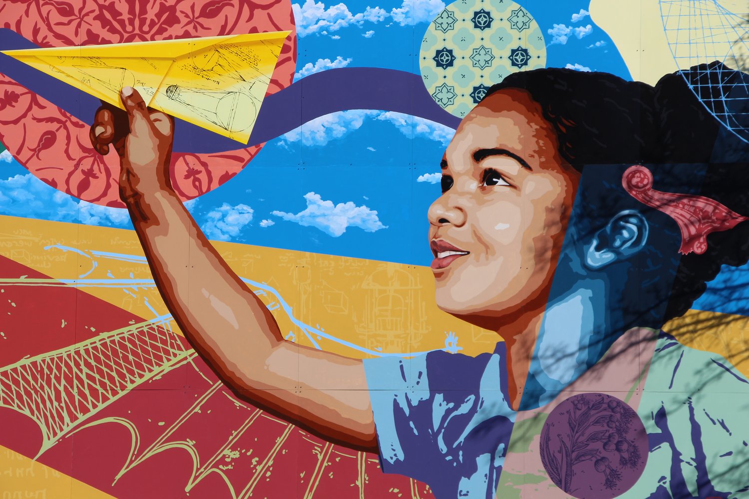 Colorful mural depicting a young child poised to throw a paper airplane